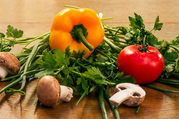 Set of good natural products with fresh yellow pepper, red tomato, mushrooms, onion and parsley on the table