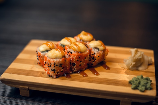 Set of hot baked rolls on a wooden tray with ginger and wasabi. Tasty sushi in a chinese restaurant