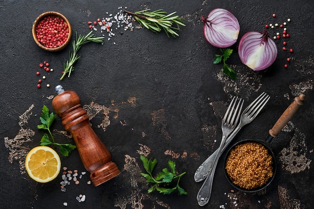 Set of Indian fragrant spices and herbs on a black stone background. Turmeric, dill, paprika, cinnamon, saffron, basil and rosemary in a spoon. Top view. Mock up.