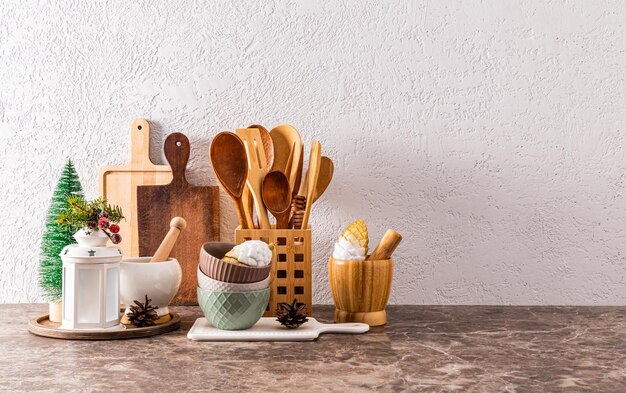 A set of kitchen utensils made of ecofriendly materials on a kitchen stone countertop with Christmas decorations in a minimalist style A copy space