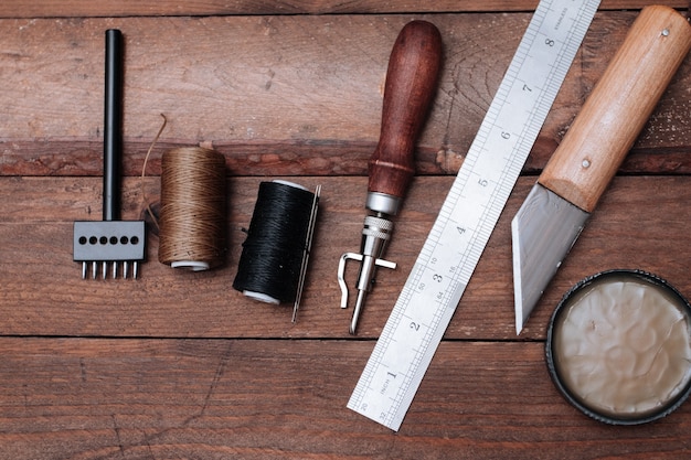 Set of Leather crafting tools. Shoes maker tools on wooden table.