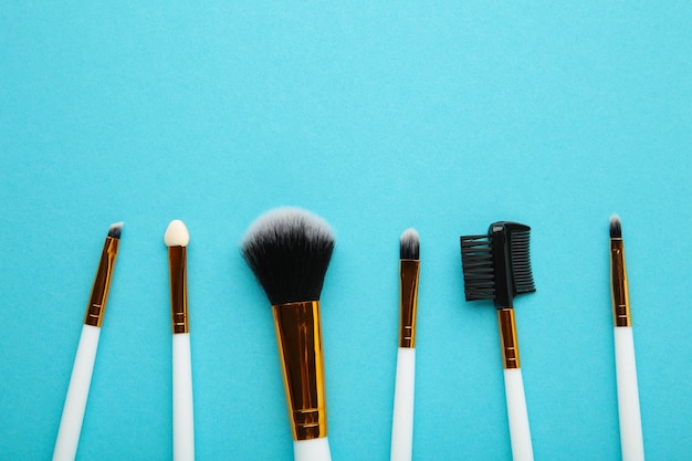 Set of makeup brushes on blue background. Top view.