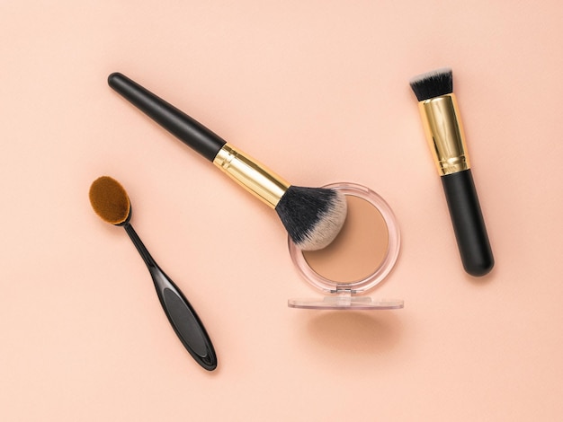 A set of makeup brushes and a jar of powder on a light pastel background Makeup device