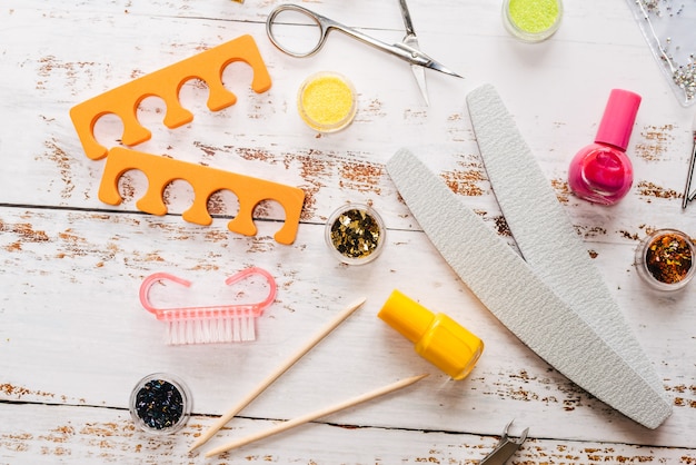 Set of manicure tools and nail polishes on white wood