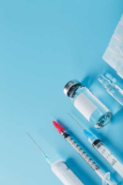 set of medical syringes and ampoules with medicines and vaccines in a row on a blue background.