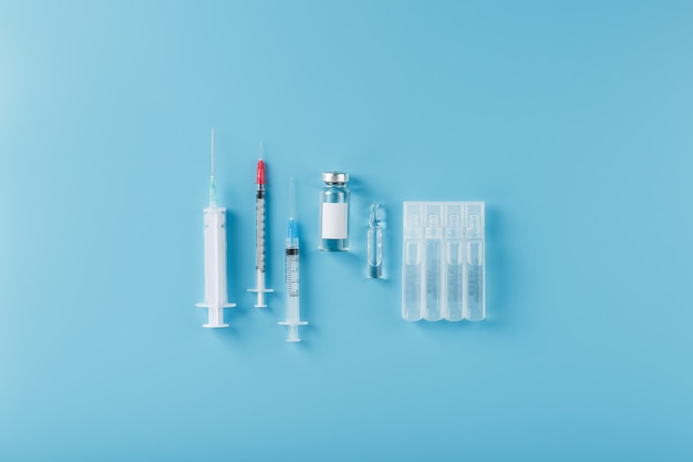 A set of medicines in ampoules and syringes for the treatment of viruses, vaccination and diseases. On a blue background, free space, top view.