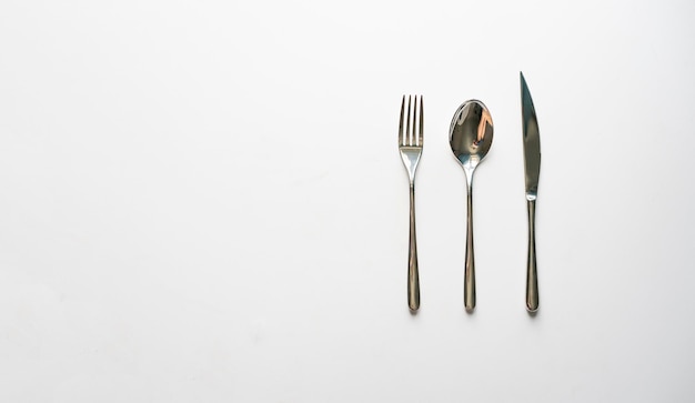 A set of metal cultery equipment on the white table spoon fork and knife