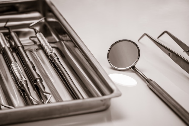 Set of metal dental instruments for dental treatment. Medical tools in stainless steel tray. Close-up view. Shallow depth of field.