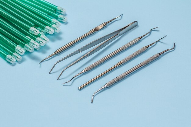 Set of metal dental instruments for dental treatment and saliva ejectors. Top view.