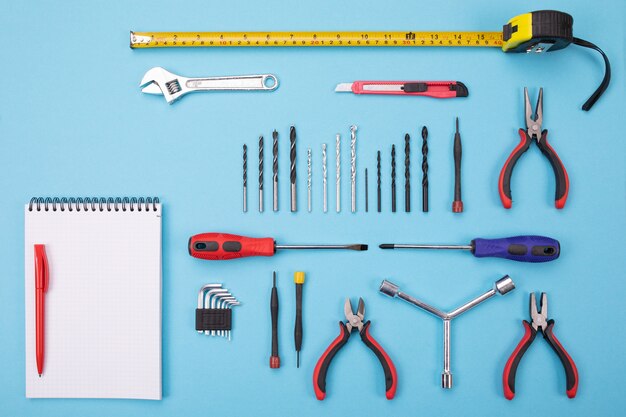 Set of metalwork tools with notebook and pen on colorful 