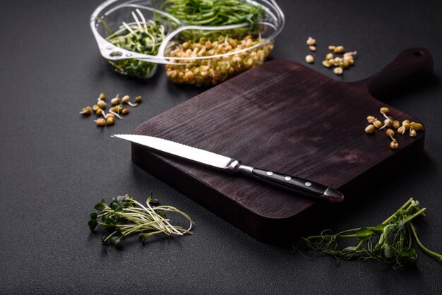 A set or mix of pea mustard and sprouted mung bean microgreens in a portioned plastic box on a dark concrete background