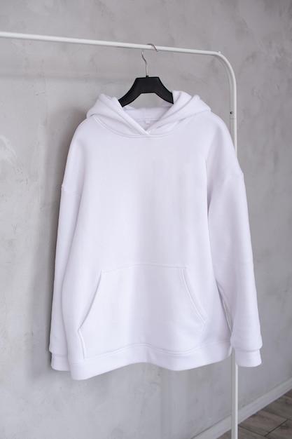 A set of mockups of a white hoodie with a hood and a pocket hanging on a hanger