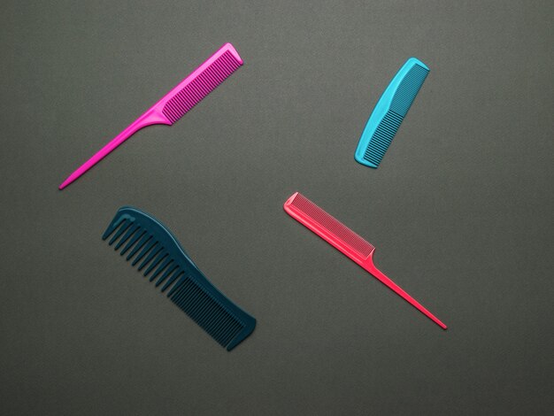 Photo a set of multi-colored combs on a dark background. a tool for hair care. flat lay.