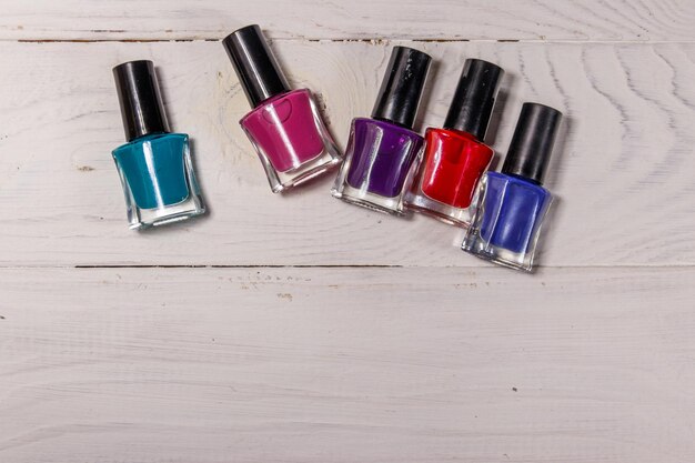 Set of nail polish bottles on white wooden background Top view copy space