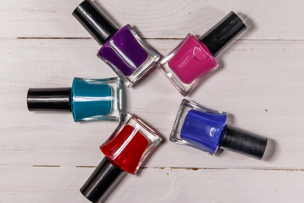 Set of nail polish bottles on white wooden background Top view