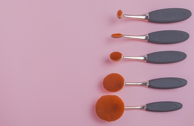 Set of oval brushes for makeup on pink background