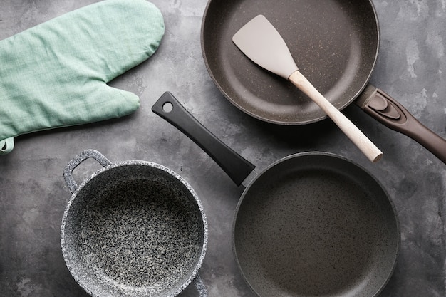 Set of pans. Various kitchen utensils on gray table, close-up.