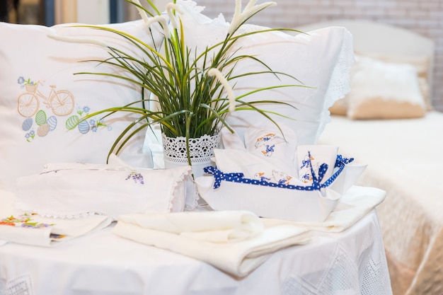 Set of pillows with neat embroidery near bed linen and green plant in household store