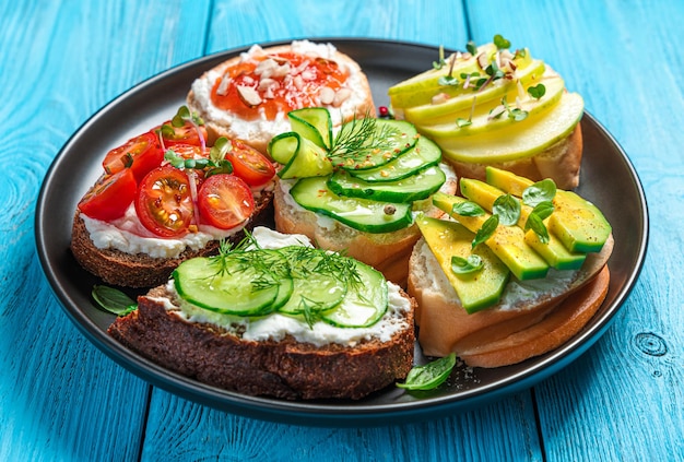 A set of sandwiches with feta ricotta vegetables and fruits on a blue background Crostini bruschetta Side view closeup