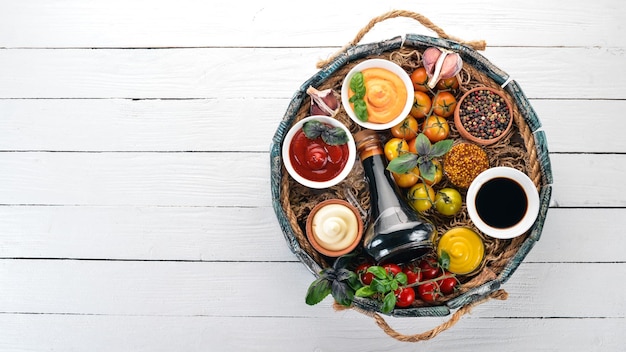 Set of sauces  Ketchup mayonnaise mustard soy sauce barbecue sauce pepper and spices On a white wooden background Top view Free space for text