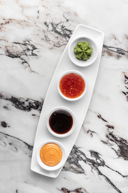 Set of sauces for sushi on a white plate wasabi spicy cheesy soy bright textured marble background top view