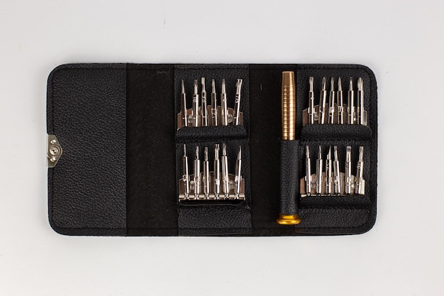 A set of screwdrivers in a leather case on a white background