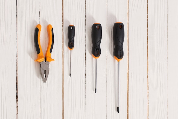 Photo set of screwdrivers and pliers on white wooden surface