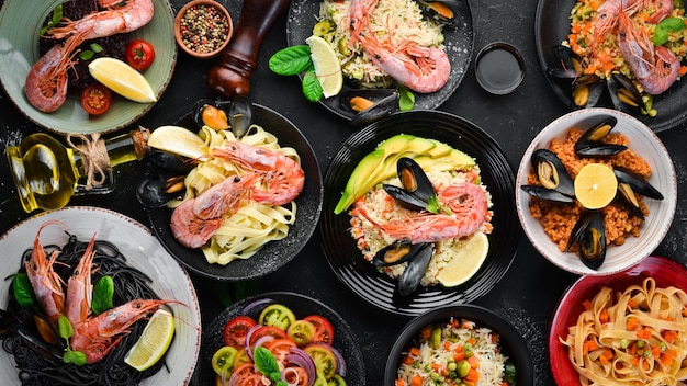 A set of seafood dishes on a black background Pasta bulgur rice couscous Top view Free space for your text