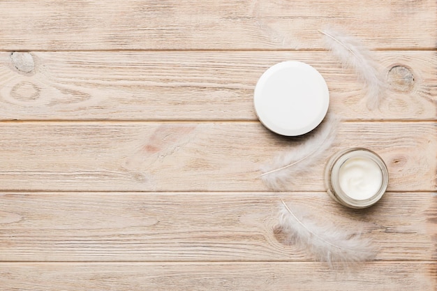 Set of skin care serums on pink pastel background with ostrich feathers Spa cosmetic product cream jar branding mock up top view with copy space