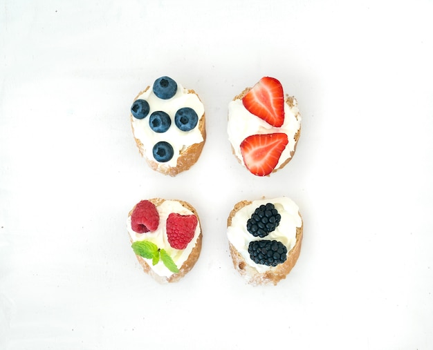 Set of small sweet sandwiches with cream-cheese and fresh forest berries