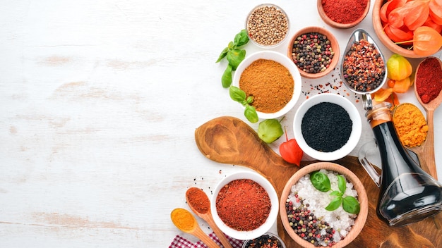 A set of Spices and herbs on a white wooden table. Basil, pepper, saffron, spices. Indian traditional cuisine. Top view. Free copy space.