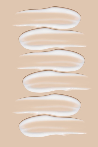 A set of strokes of white cream on a beige background