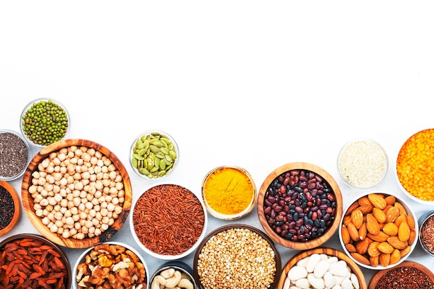 Set of superfoods legumes cereals nuts seeds in bowls on white background Superfood as chia spirulina beans goji berries quinoa turmeric and other Copy space top view