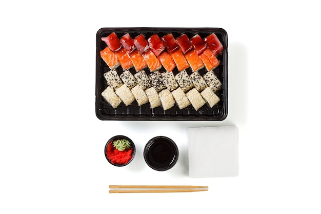 A set of sushi in a delivery box soy sauce chopsticks wasabi ginger on a white background