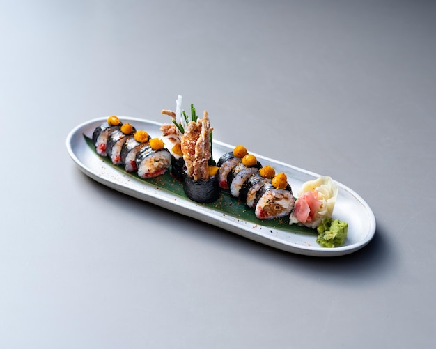 Set of sushi and maki rolls on special white plate standing at grey stone table