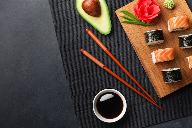 Set of sushi and maki rolls with sliced avocado on stone table. Top view.