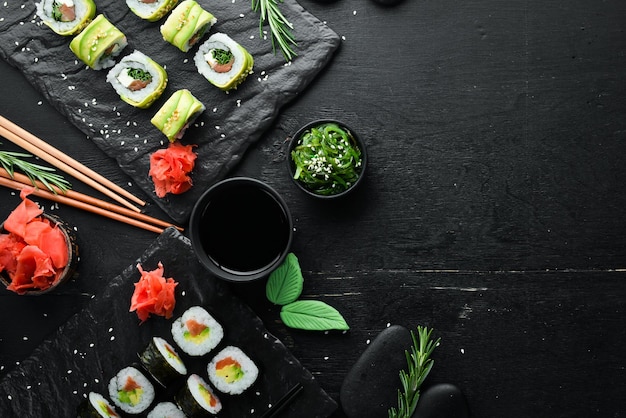 Set of sushi rolls with ginger wasabi and soy sauce on a black stone background Japanese Traditional Cuisine Top view Rustic style