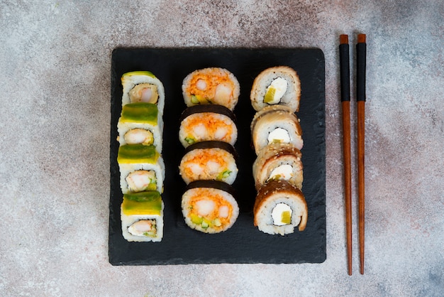 Set of sushi rolls with vegetables, cream cheese and shrimp. Traditional Japanese food on a concrete background. Top view