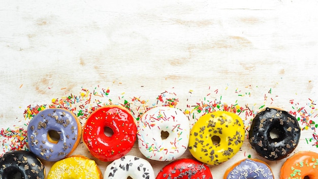 Set of sweet colored donuts on a white wooden background. Top view. Flat Lay.