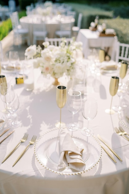 Set table with glasses and bronze goblets with a bouquet of flowers stands in the garden