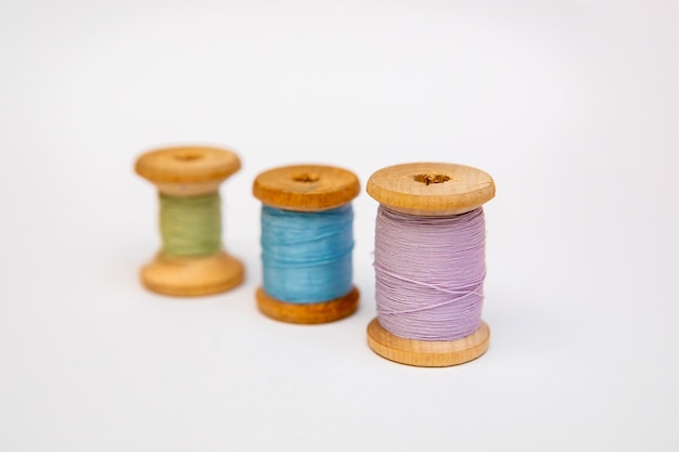 Set of tailoring accessories. Close up of a stack of folded pink fabric, sewing scissors, and spools of thread