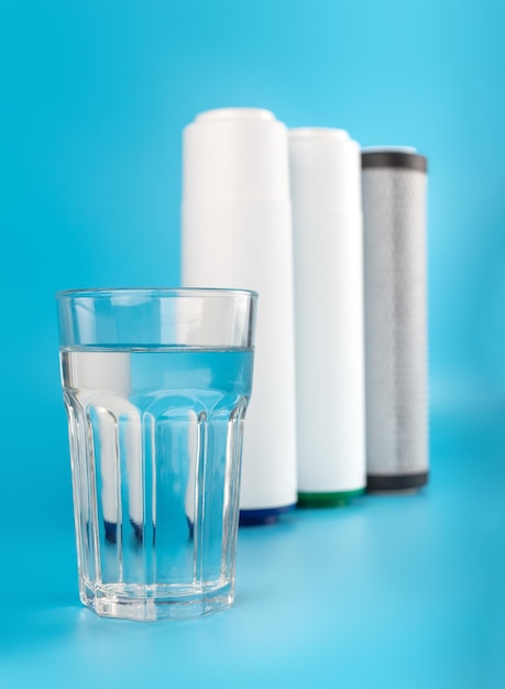 Photo set three of cartridges for water filter with clear glass of water on blue background concept water