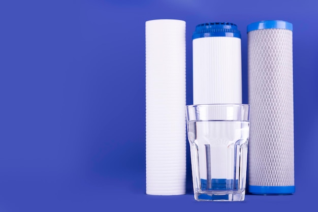 Photo set three of cartridges for water filter with clear glass of water isolated on violet background