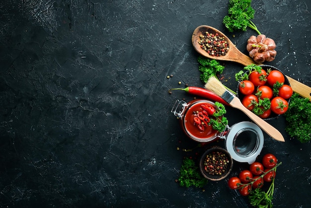 A set of tomato sauces on a black stone background Ketchup barbecue sauce tomato sauce Top view Free space for your text