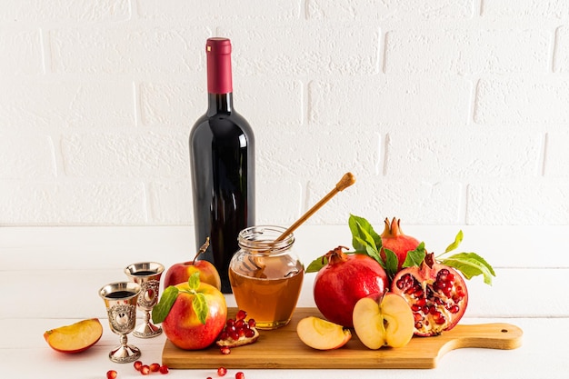 A set of traditional food and a bottle of red wine for Rosh Hashanah against the backdrop of a white brick wall front view Jewish New Year