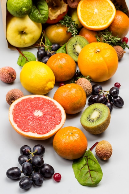 Set of varied, multicolored exotic fruits. Mandarins, grapefruit, lychee, kiwi and grapes with chard leaves. Grey background. Top view