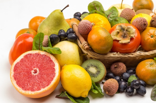 Set of varied, multicolored exotic fruits. Mandarins, grapefruit, lychee, kiwi and grapes with chard leaves. White background. Top view
Close up