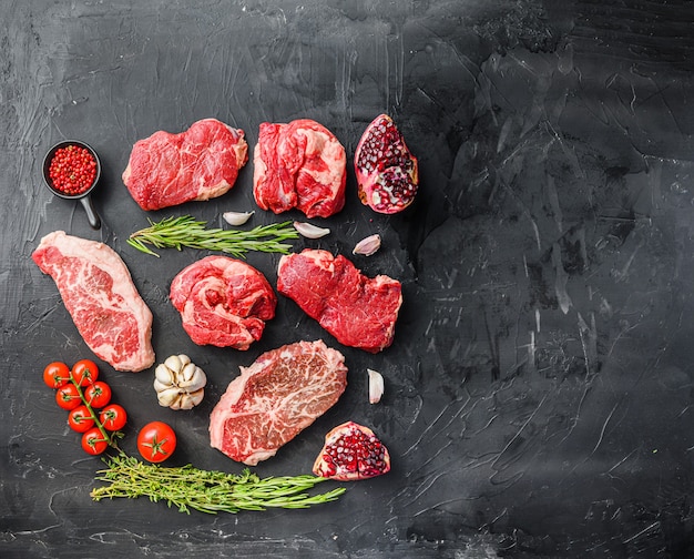 Set of various classic, alternative steaks picanha, ramp and chuck eye roll and top blade over black background top view. Big size space for text