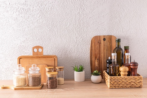 A set of various kitchen utensils and cans bottles for food storage wooden cutting boards on a wooden countertop in a modern kitchen