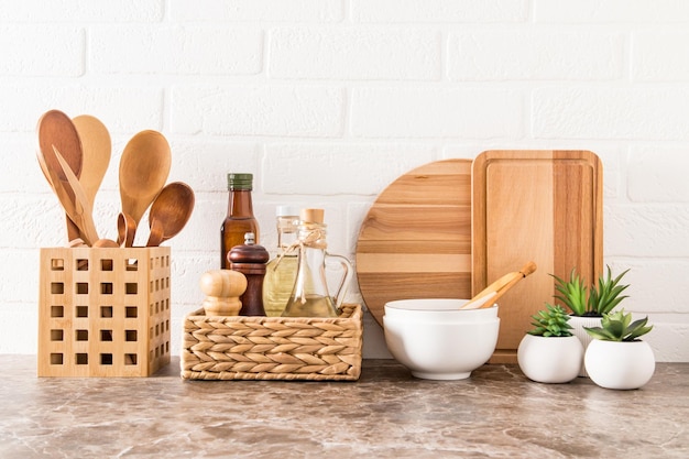 A set of various modern kitchen utensils on a marble countertop against a white brick wall ecofriendly materials without plastic